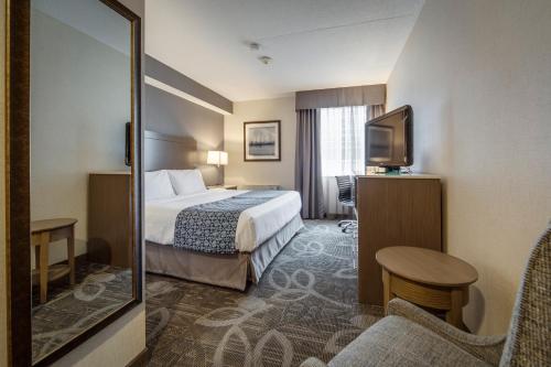 a hotel room with a bed and a television at Monte Carlo Inn Airport Suites in Mississauga