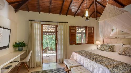 a bedroom with a bed and a desk and a window at Ananda Pousada in Pirenópolis