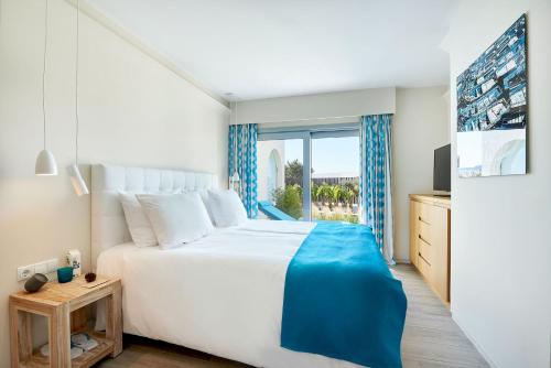 a white bedroom with a large bed and a window at 7Pines Resort Ibiza, part of Destination by Hyatt in San Jose