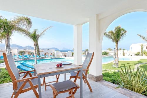 a table and chairs on a patio with a pool at 7Pines Resort Ibiza, part of Destination by Hyatt in San Jose
