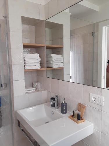 a white bathroom with a sink and a mirror at h-sa GUEST HOUSE in Matera