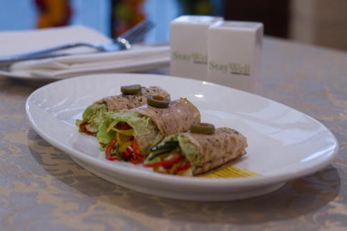 a white plate with a sandwich on a table at Leisure Inn Grand Chanakya in Jaipur
