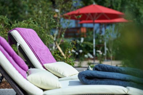 a group of chairs with pillows and an umbrella at Hotel Appartement Roggal in Lech am Arlberg
