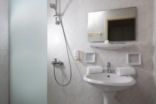a bathroom with a sink and a shower with a mirror at Rainbow Apartments in Stalida