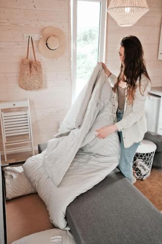 a woman is putting a blanket on a bed at Raceway Baltic cabins in Silakrogs