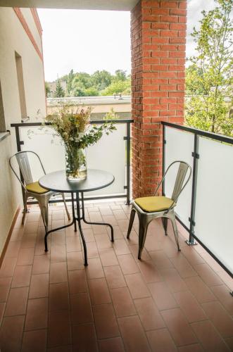 a balcony with a table and chairs and a vase with flowers at ART Pensjonat in Krotoszyn