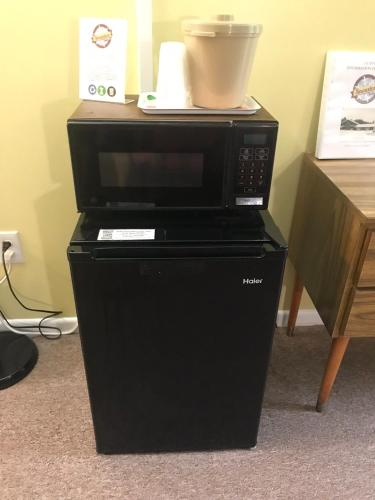 a black microwave oven sitting on top of a refrigerator at Snowdon Chalet Motel in Londonderry