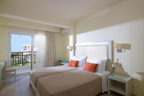 a hotel room with a bed with two orange pillows at Rainbow Apartments in Stalida