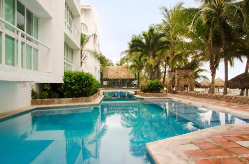 a swimming pool in front of a building with palm trees at Hotel Villa Varadero in Nuevo Vallarta 