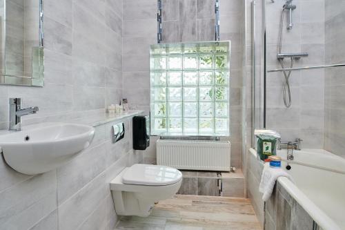 uma casa de banho com um lavatório, um WC e uma banheira em Hylands Burren Hotel em Ballyvaughan