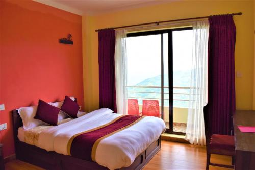 a bedroom with a bed with a large window at Hotel Nagarkot Inn in Nagarkot