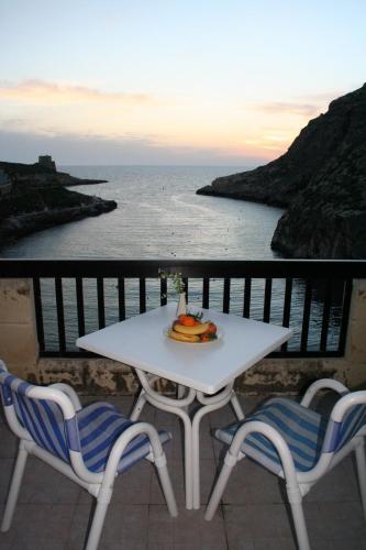 a table and chairs on a balcony with the ocean at St. Patrick's Hotel in Xlendi