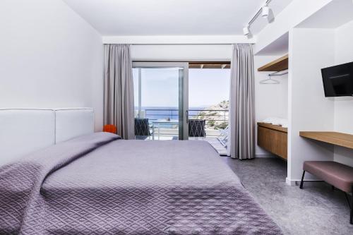 a bedroom with a bed and a view of the ocean at Paralos Lodging in Schinoussa