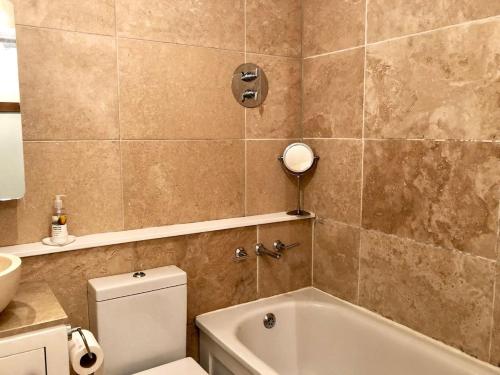 a bathroom with a tub and a toilet and a sink at Lauras Townhouse Apartments Garrard's Retreat in Bath
