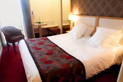 a hotel room with a bed, chair, and nightstand at Le Relais Du Roy in Le Mont Saint Michel