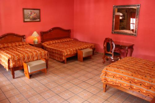 a red room with two beds and a mirror at Hotel Boutique Posada la Casona de Cortés in Tlaxcala de Xicohténcatl