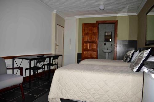 a bedroom with a bed and a desk and a table at 13 Hobson in Secunda