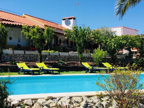 a swimming pool with yellow chairs and a house at Quinta Da vida Serena in Gaio