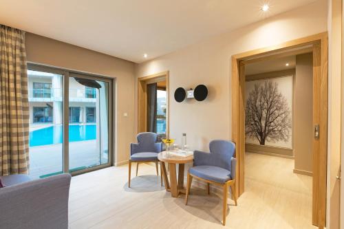 a dining room with a table and chairs and windows at Eden Roc Resort - All Inclusive in Kallithea Rhodes