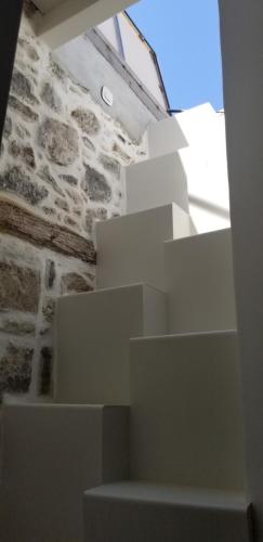 a room with a stone wall and white stairs at Amaranti House n Art in Mandrakion