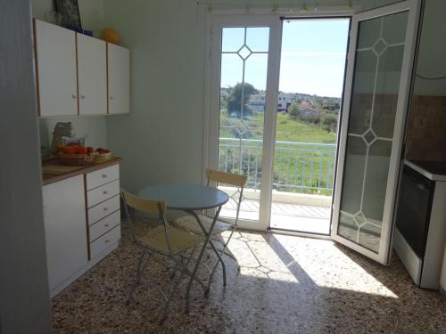 a kitchen with a table and a view of a balcony at Sun and Sea in Souvala