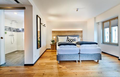 two beds in a bedroom with a shower at Hotel & Restaurant Herzstück Waldkirchen in Waldkirchen