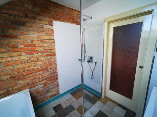 a bathroom with a glass shower and a brick wall at Penzion Okamžik Stanovice in Nová Cerekev