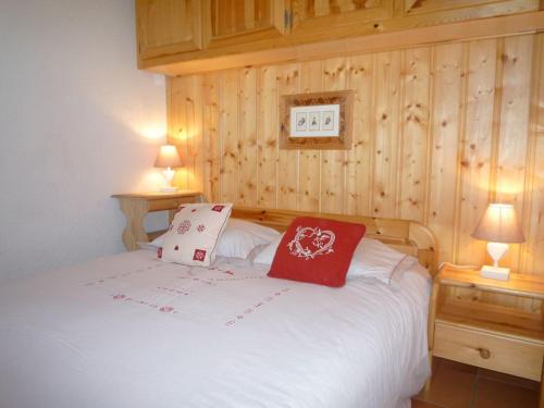 a bedroom with a white bed with two red pillows at Le Panda in Les Carroz d'Araches
