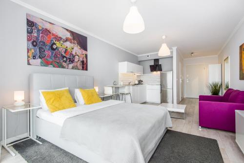 a bedroom with a white bed and a purple couch at Super-Apartamenty Old Market in Poznań