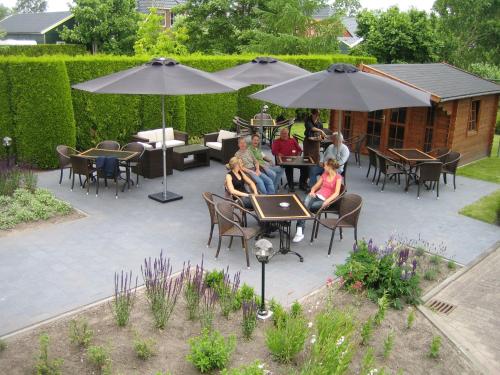 a group of people sitting on a patio under umbrellas at Hotel Ekamper in Oosteinde