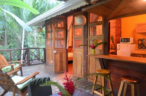 Pachamama Jungle River Lodge - Punta Uva في بويرتو فيجو: غرفة بها شرفة مع كراسي ومطبخ