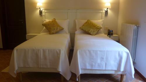 a bedroom with two beds with white sheets and yellow pillows at Chiosi Country Club in Corleone