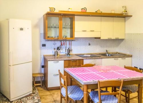 a kitchen with a table and a white refrigerator at CàSerena in Alghero