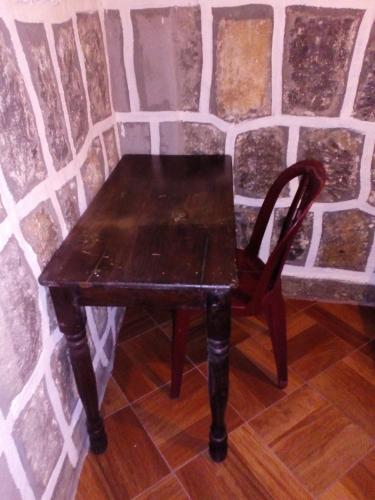 a wooden table and a chair in front of a wall at Casa LLEMO in San Pedro La Laguna
