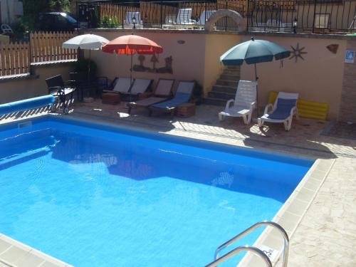 a large swimming pool with chairs and umbrellas at The Pink House in Polkownik Serafinowo