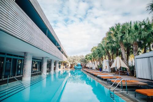 a swimming pool in front of a building with palm trees at SLS South Beach in Miami Beach