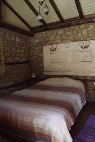 1 dormitorio con 1 cama en una pared de piedra en The Pink House, en Polkownik Serafinowo