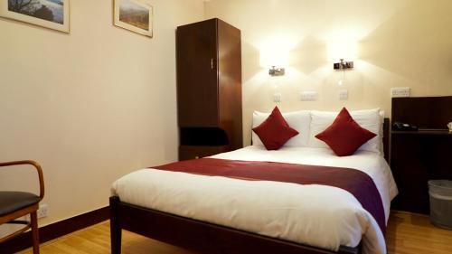 Cette chambre comprend un grand lit avec des oreillers rouges. dans l'établissement La Gaffe - Bed and Breakfast, à Londres