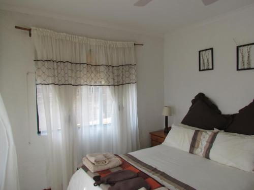 a bedroom with a bed and a window with white curtains at Pumula Guest Farm in Fouriesburg