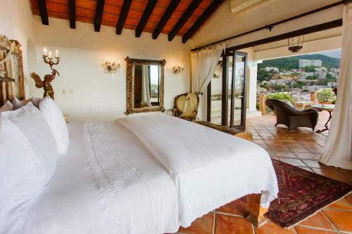 a bedroom with a large white bed and a balcony at Hacienda San Angel in Puerto Vallarta