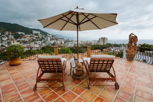a patio with two chairs and an umbrella at Hacienda San Angel in Puerto Vallarta