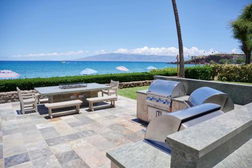 a patio with a grill and a table and chairs at Aston at The Whaler on Kaanapali Beach in Lahaina