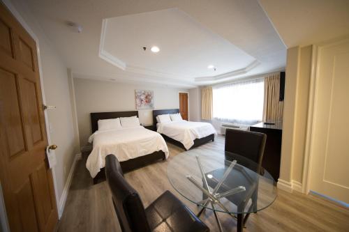 a hotel room with two beds and a glass table at Wilshire Crest Hotel in Los Angeles