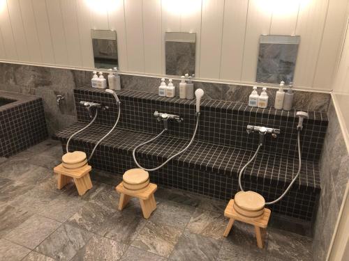 a bathroom with three faucets and three wooden stools at Hotel Hikari Hills in Shunan