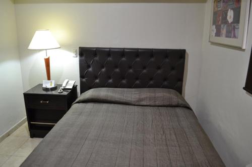a bed with a black headboard and a night stand at Hotel America Centro in Los Mochis