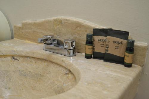 La salle de bains est pourvue d'un lavabo avec 2 bouteilles. dans l'établissement Hotel America Centro, à Los Mochis