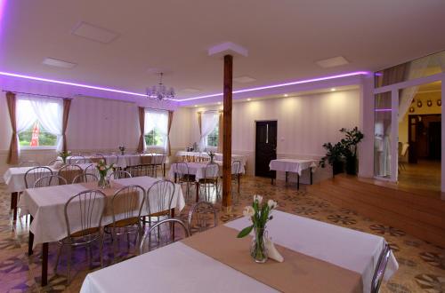 un salón de banquetes con mesas y sillas blancas e iluminación púrpura en Zajazd Ostoja, en Stary Dzierzgoń