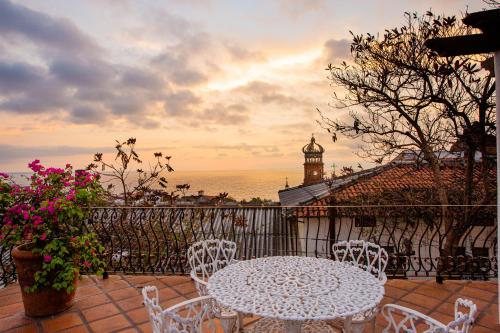 a white table and chairs on a balcony with a clock tower at Hacienda San Angel in Puerto Vallarta