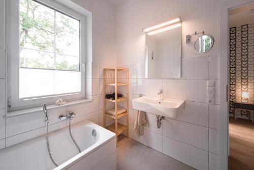 ein Bad mit einer Badewanne, einem Waschbecken und einem Fenster in der Unterkunft 5 Sterne Ferienwohnungen am See in Bad Zwischenahn