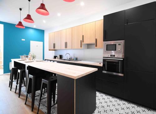 une cuisine avec des placards noirs et un îlot de cuisine avec un four micro-ondes dans l'établissement An authentic experience with spa in the center, à Poitiers